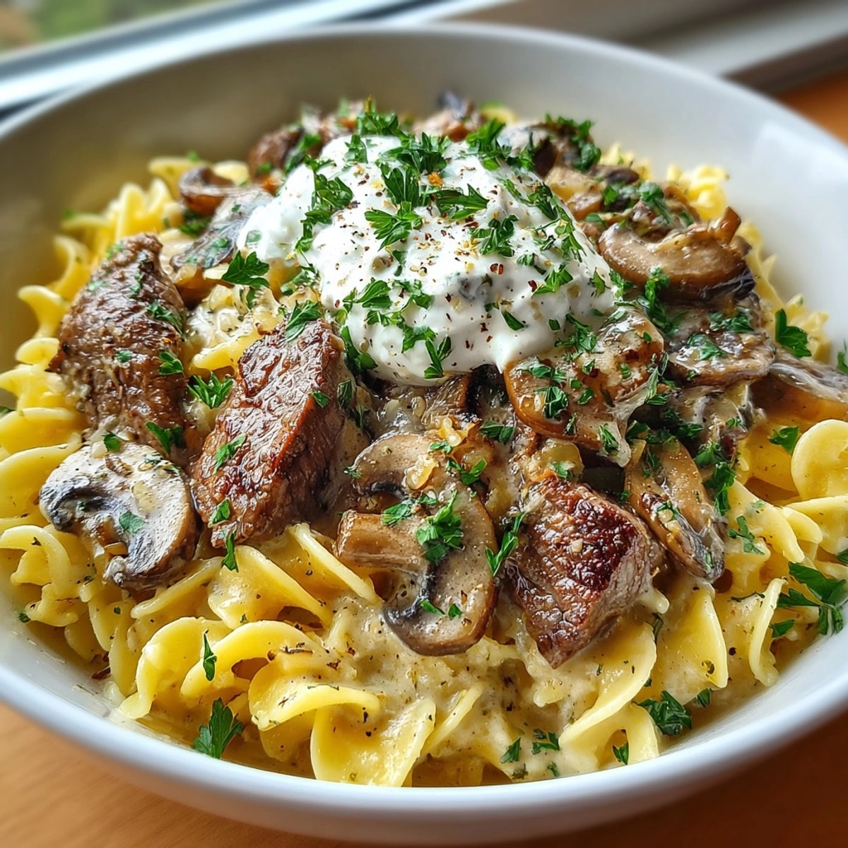 Tender beef strips and mushrooms over egg noodles in one-pot beef stroganoff, garnished with parsley.