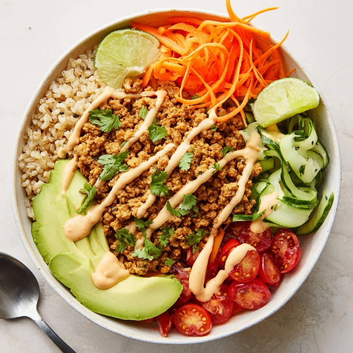 Delicious plant-based meat bowl topped with fresh veggies and creamy sriracha sauce.  