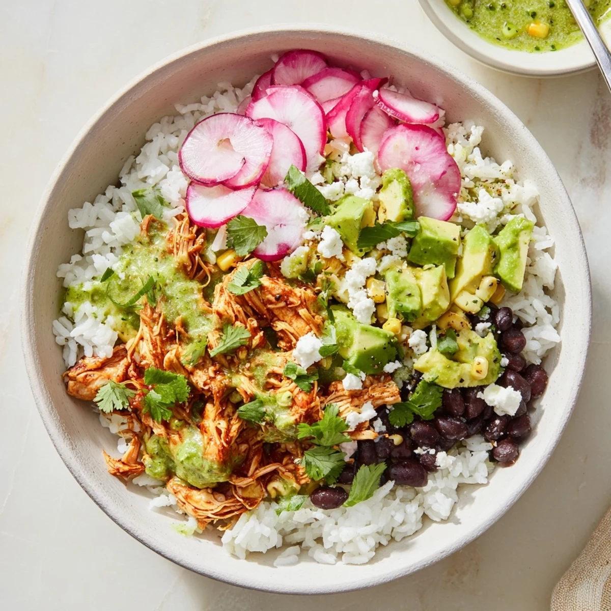 Healthy green enchiladas rice bowl garnished with cilantro, radishes, and a lime wedge.