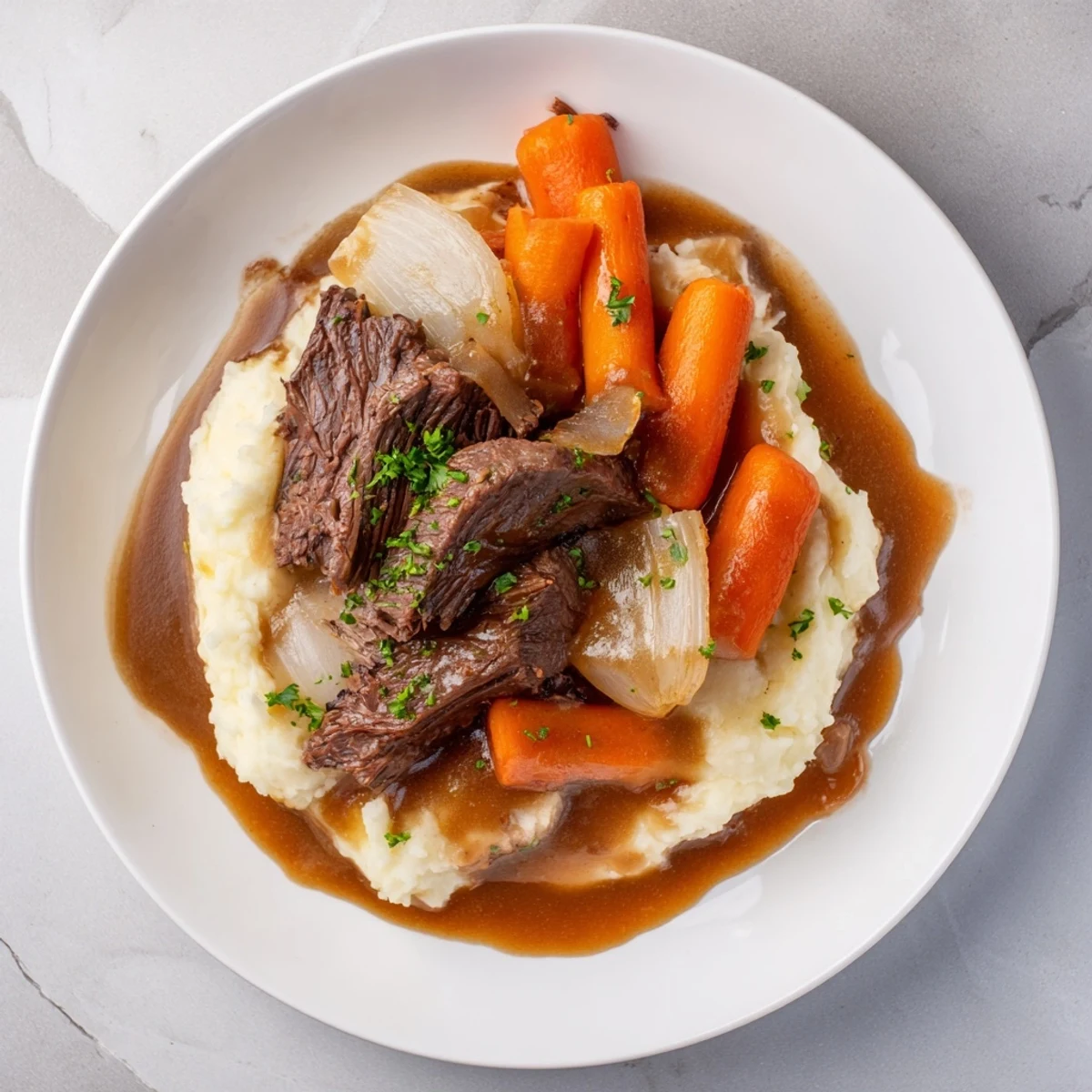 Tender slow cooker pot roast with carrots, a savory family meal atop mashed potatoes.