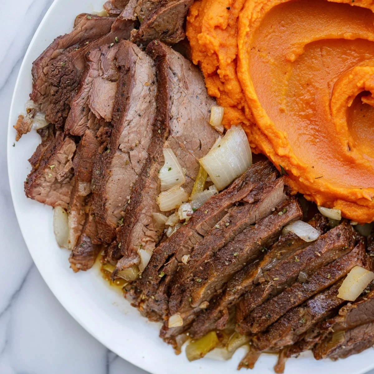 Fork-tender Classic Brisket, glistening with sauce, next to creamy, dreamy mashed sweet potatoes.