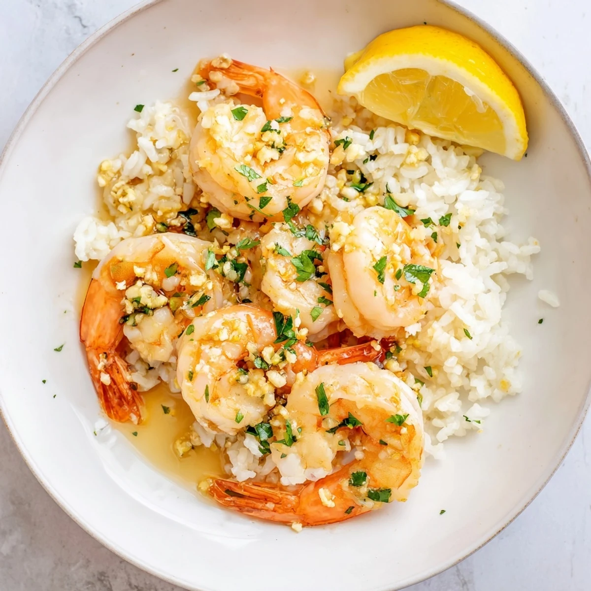 A delicious Garlic Butter Shrimp Rice Bowl, garnished with parsley and lemon wedges for a perfect meal.