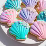 Freshly baked Seashell Sweets, intricately iced and dusted with shimmer, offer delightful, sweet texture.