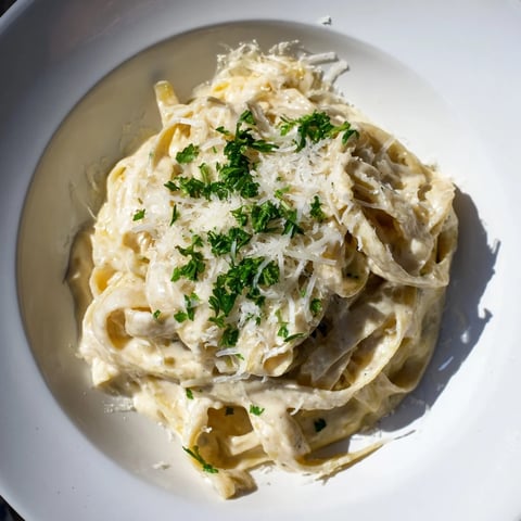 Steaming hot Skinny Alfredo Garlic Parmesan Pasta, coated in creamy, Parmesan-infused sauce with parsley garnish.