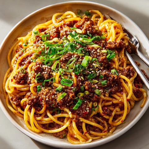 Close-up of sticky Spicy Honey Garlic Beef Spaghetti, glistening sauce over tender noodles and juicy beef.