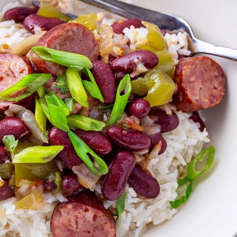Flavorful Red Beans & Rice garnished with green onions and hot sauce.  