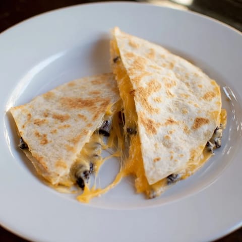 Melted cheese spills from folded Bean & Cheese Quesadillas, a simple yet satisfying Mexican lunch.