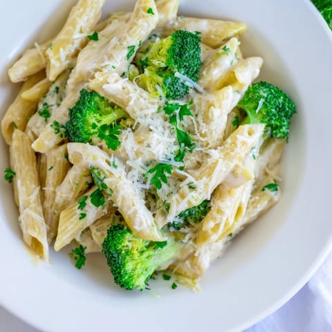 Enjoy a steaming bowl of cream cheese garlic pasta, with Parmesan and fresh parsley garnish.