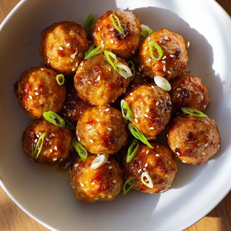 A close-up of steaming Spicy Honey-Glazed Chicken Meatballs glistening and ready to serve.
