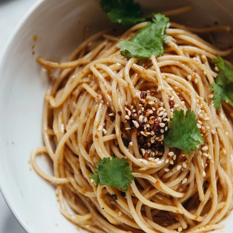 Serving suggestion for Spicy Sesame Noodle Salad, garnished with spring onions and paired with iced green tea.