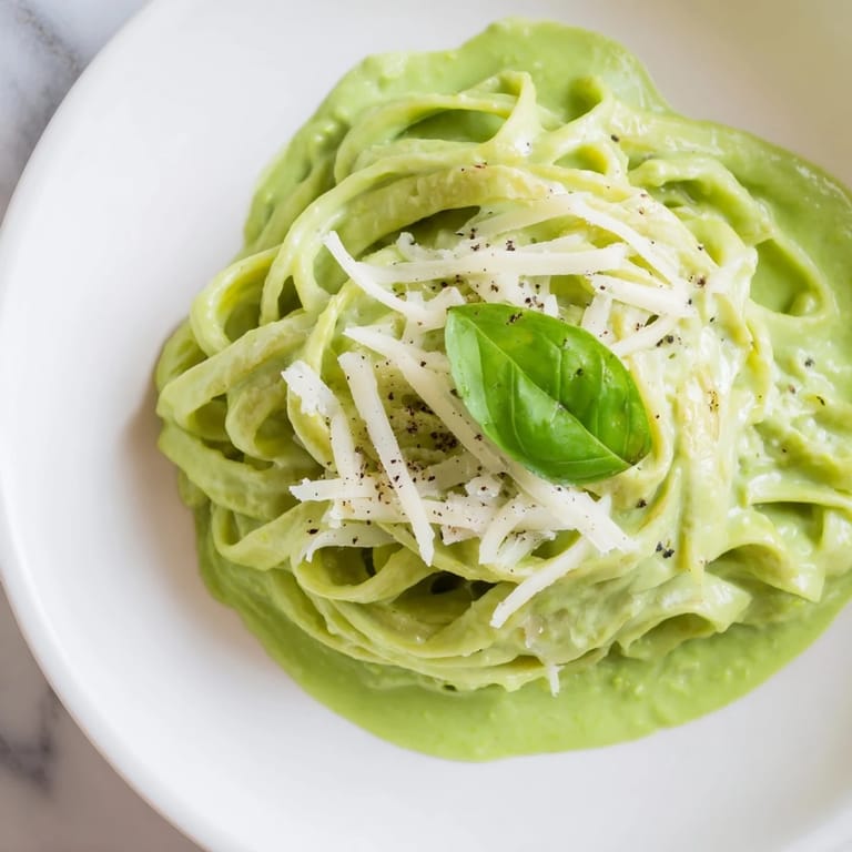 A comforting bowl of Creamy Green Pea Alfredo served as a vegetarian main dish, with steam rising and peas dotting the pasta.